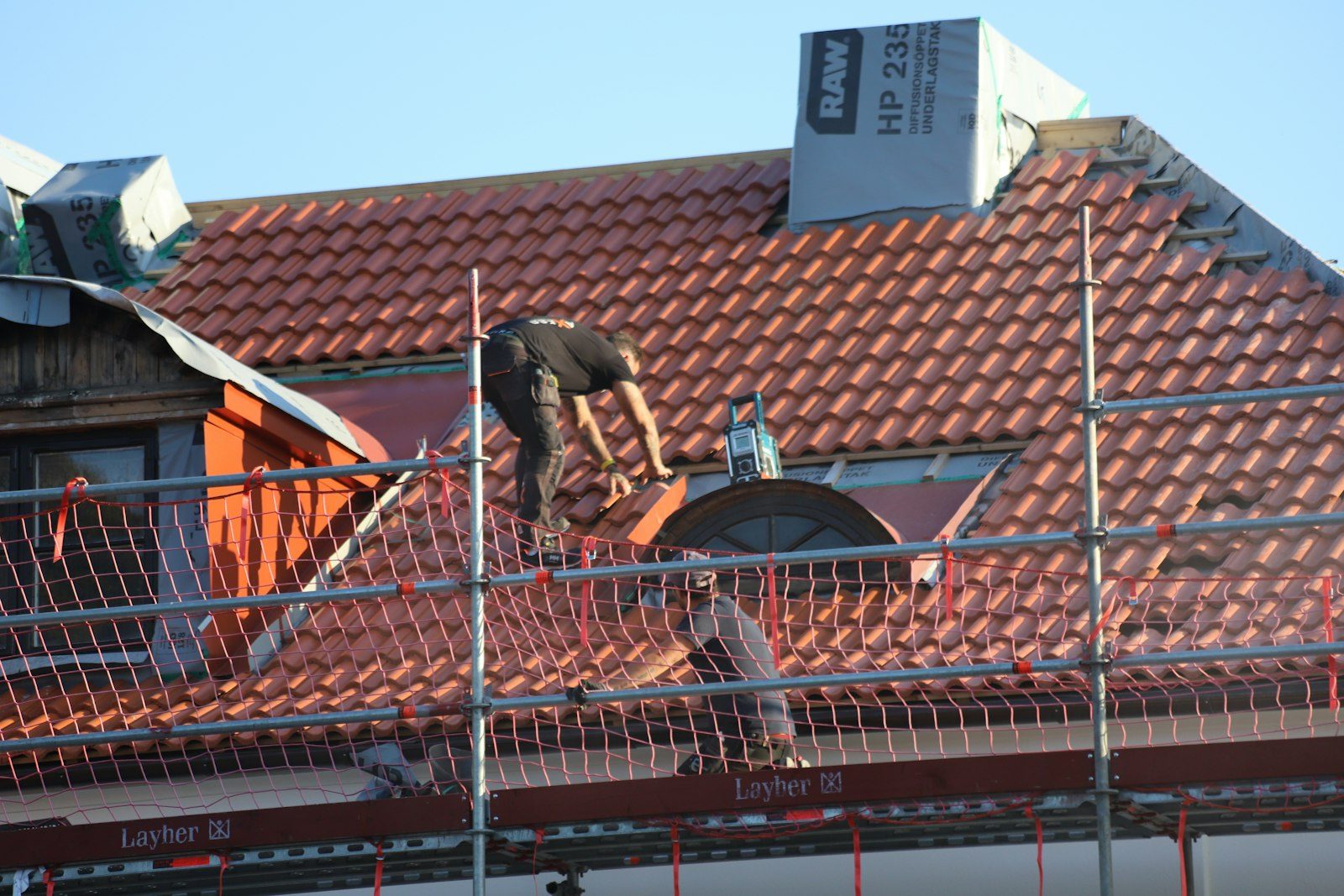 Dakdekker aan het werk op een pannendak met steiger
